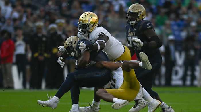 Notre Dame safety Ramon Henderson (11) and Irish linebacker Marist Liufau (8) tackle Navy fullback Daba Fofana.